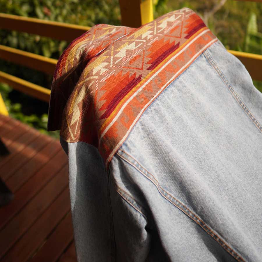 Chevere Ethno-Jeansjacke unisex. Detail der Rückseite mit Ethno-Muster in Orange.